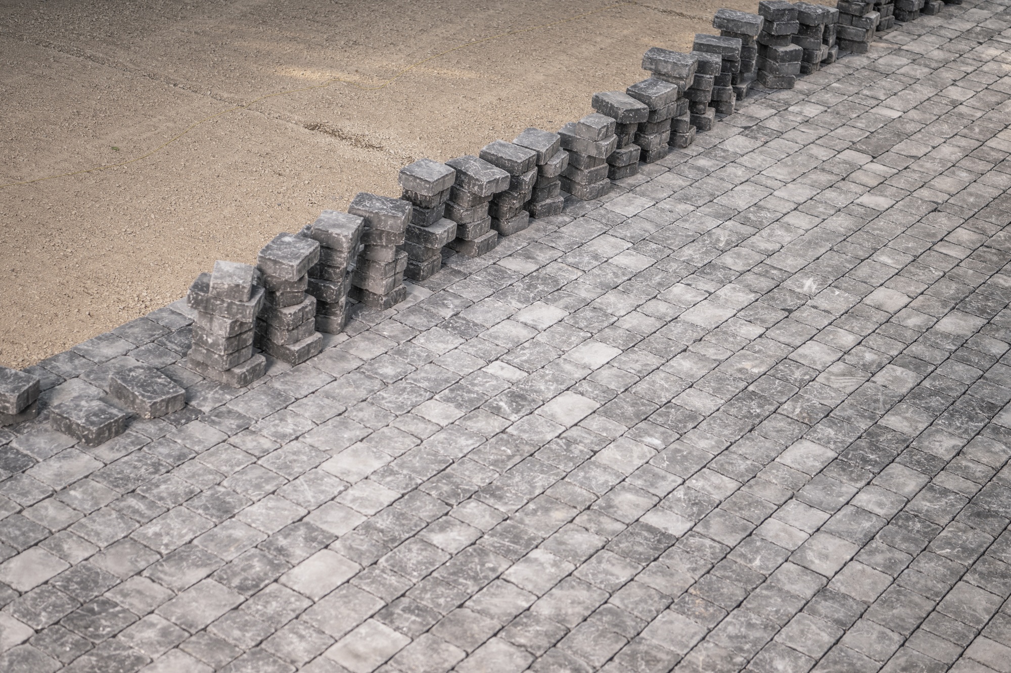 Newly Laid Cobblestones Next to Stacked Paving Stones in Urban Development